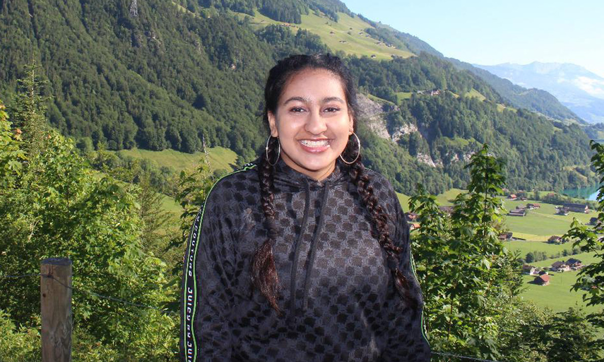 University student Khushi Jain, smiling at the camera with a beautiful green landscape behind her