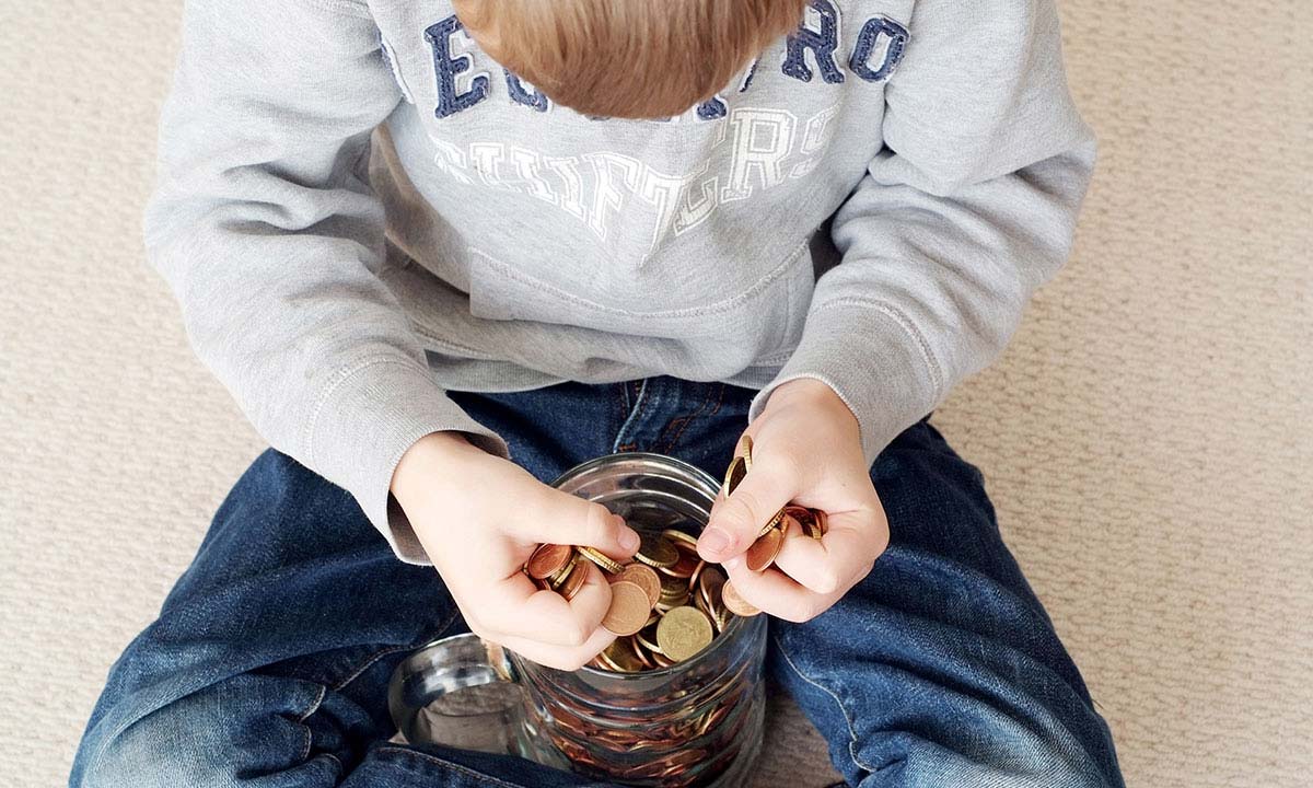 Young boy counts money from a savings jar